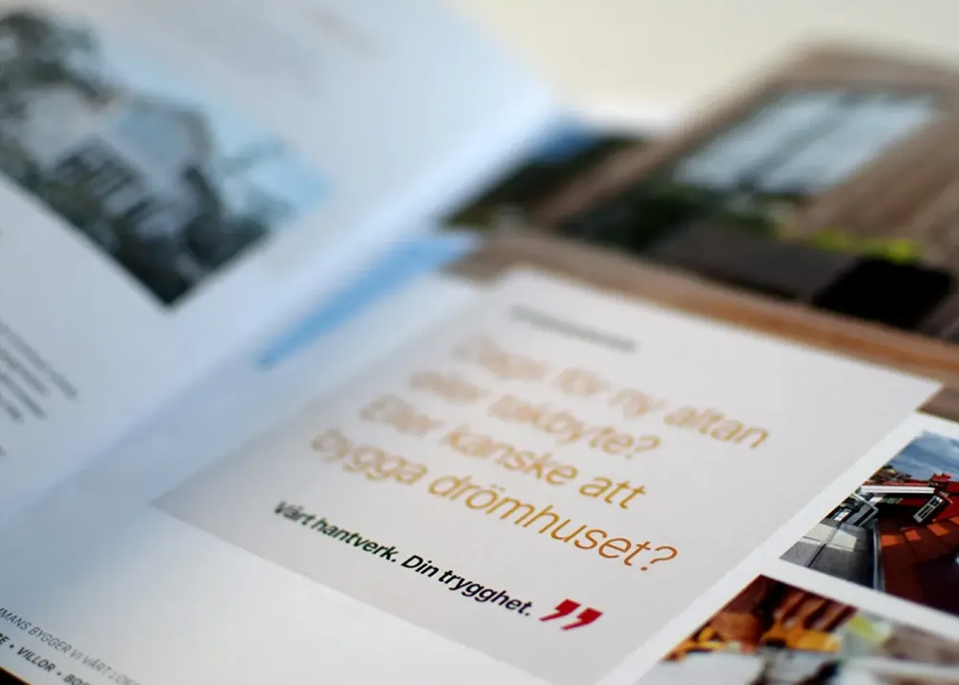 En närbild av en öppen tidningssida med svensk text och suddiga bilder. Den synliga texten lyder: Dags för ny altan eller takbyte? Eller kanske att bygga drömhuset? Vårt hantverk. Din trygghet.