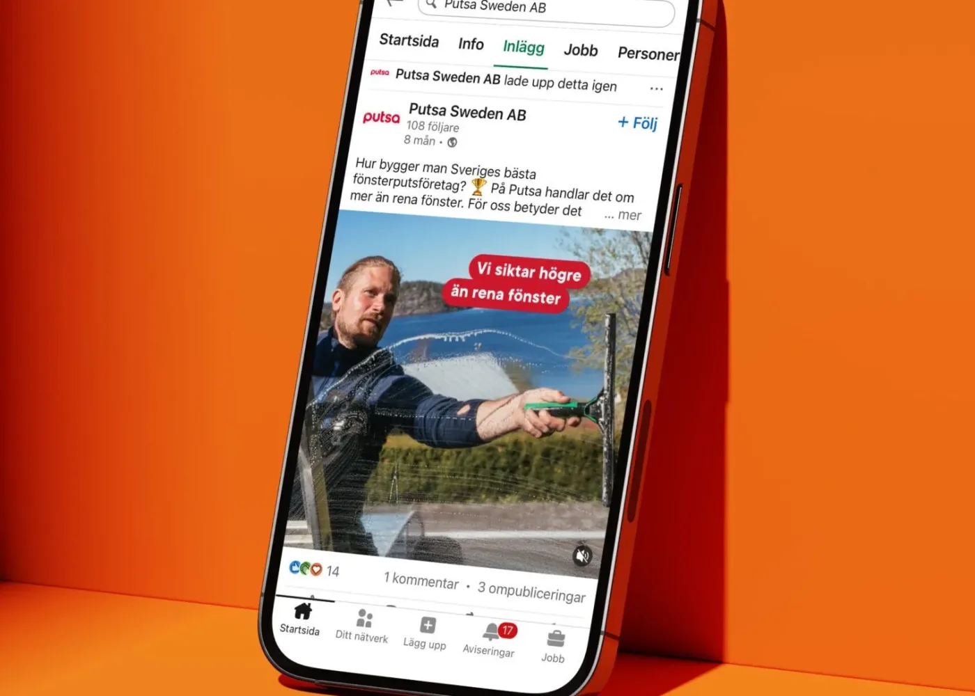 En smartphone med ett LinkedIn-inlägg på skärmen är placerad mot en orange yta. Inlägget visar en man som putsar ett fönster, med svensk text och grafik som lyfter fram fönsterputsningstjänster.
